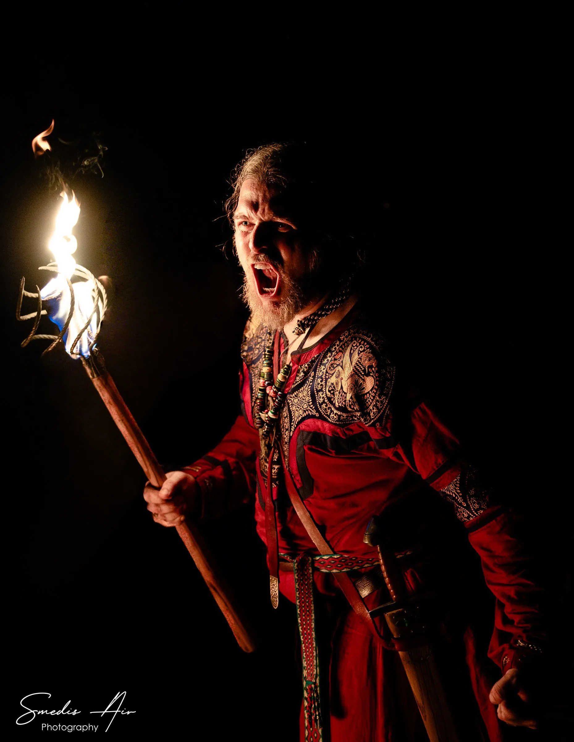 Performer in a red costume holding a burning torch at night