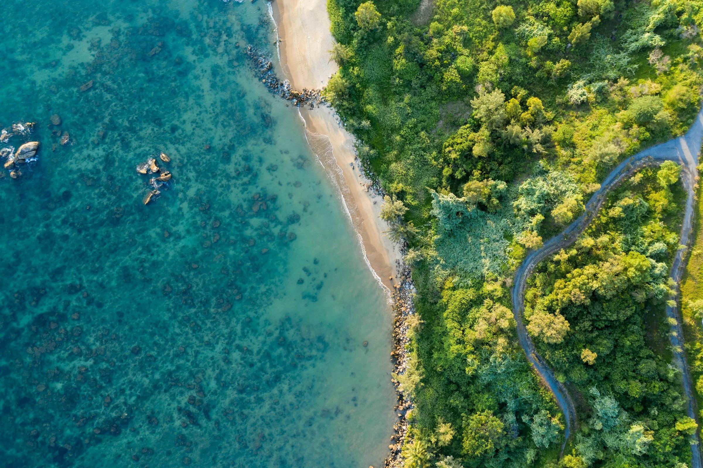 Aerial view of a coastline where a winding road meets a turquoise sea